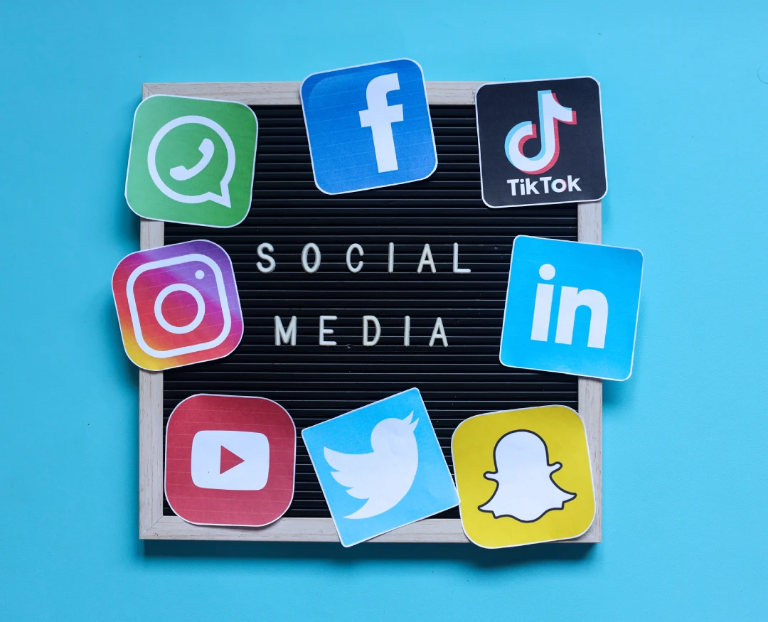 Social Media written on a small, square black board with papercuts of social media logos around it